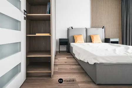 Sypialnia w stylu japandi z szarym łóżkiem i minimalistycznym wystrojem.