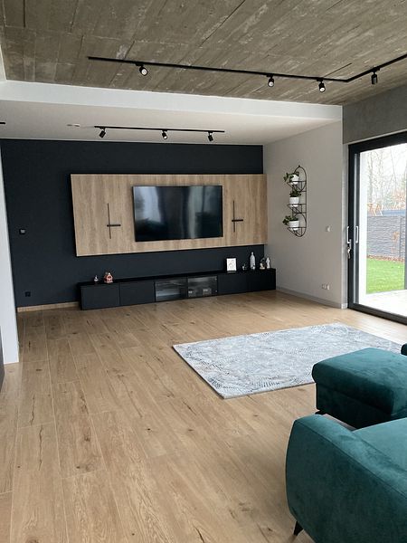 Wnętrze nowoczesnego salonu z telewizorem i drewnianymi elementami.