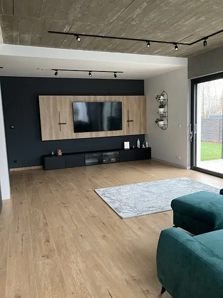 Wnętrze nowoczesnego salonu z telewizorem i drewnianymi elementami.