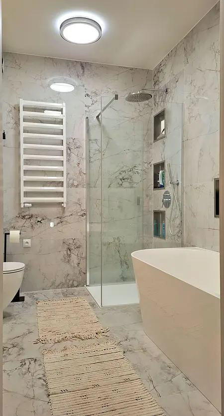 Nowoczesna łazienka z wanną, prysznicem i marmurowymi płytkami.