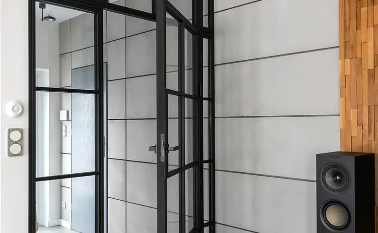 Przedpokój w stylu industrialnym z minimalistycznymi drzwiami i drewnianymi akcentami.