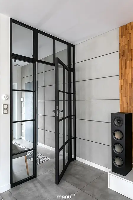 Przedpokój w stylu industrialnym z minimalistycznymi drzwiami i drewnianymi akcentami.