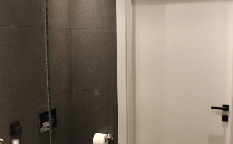 Nowoczesna łazienka z minimalistycznym designem, szare płytki, biała umywalka.