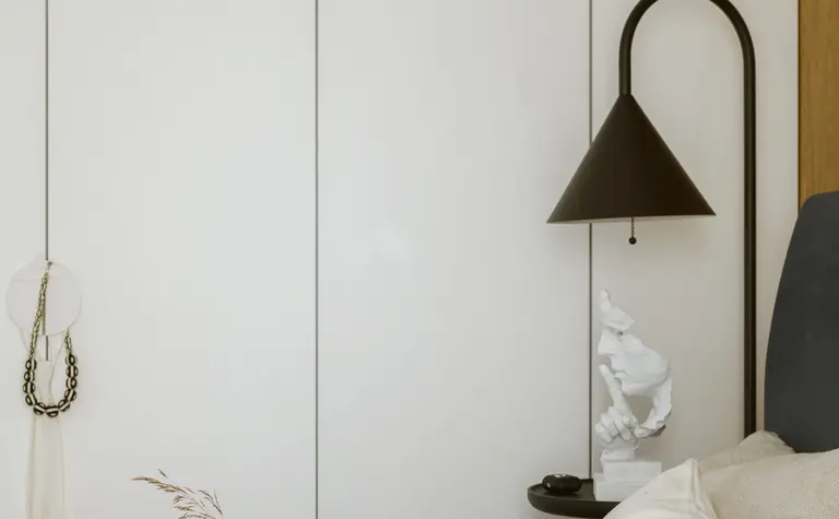 Przytulna sypialnia z białymi ścianami, brązowymi akcentami, lampą w stylu industrialnym, boho i soft minimalizmem.