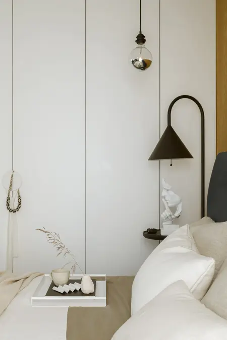 Przytulna sypialnia z białymi ścianami, brązowymi akcentami, lampą w stylu industrialnym, boho i soft minimalizmem.