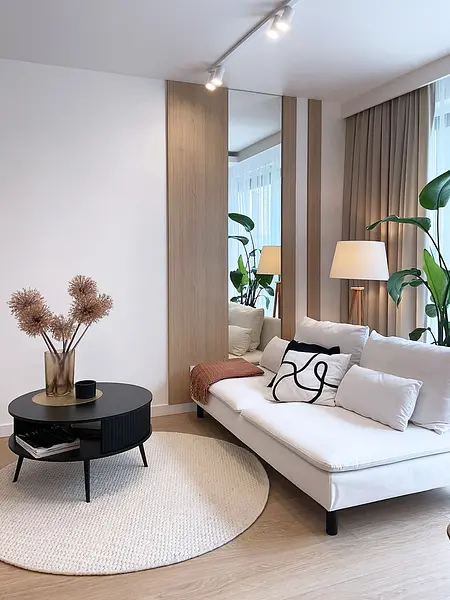 Wnętrze salonu w stylu glamour i minimalistycznym z roślinami.