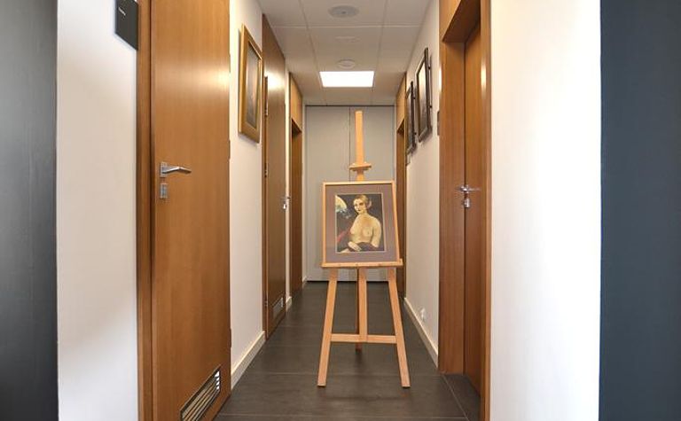 Korytarz w stylu minimalistycznym z obrazem na sztaludze i drewnianymi akcentami.