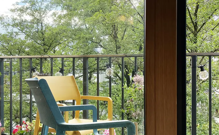Balkon z kolorowymi krzesłami, roślinami i widokiem na zieleń, minimalistyczny, nowoczesny.