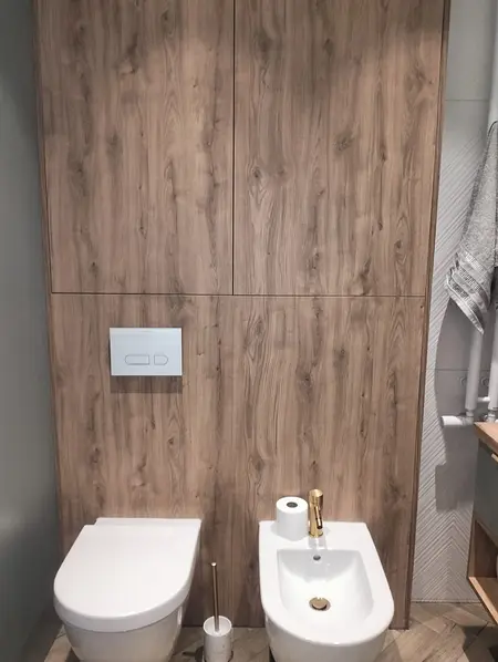 Nowoczesna toaleta z drewnianymi ścianami i białymi ceramikami.