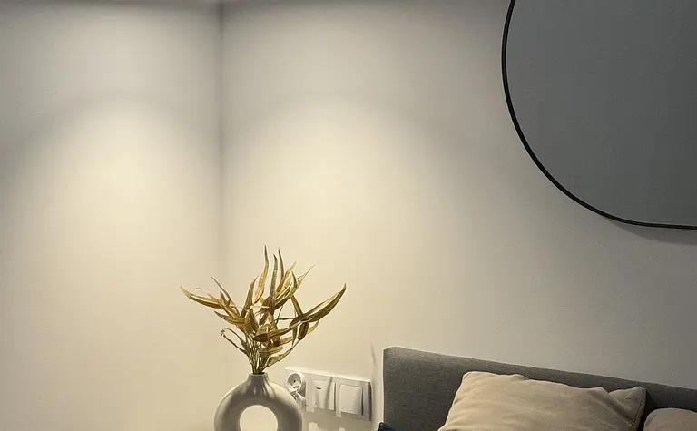 Wnętrze sypialni w stylu boho, minimalistycznym i rustykalnym z szarym łóżkiem i dekoracyjną lampą.
