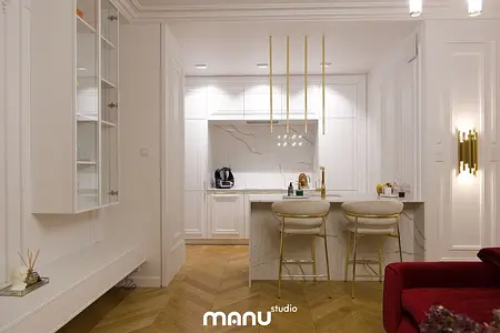 Wnętrze kuchni w stylu nowoczesnym z białymi meblami i złotymi detalami.
