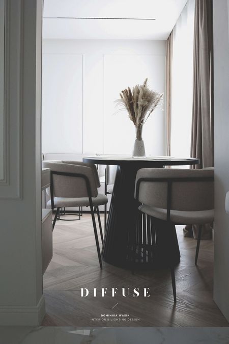 Jadalnia w stylu boho i minimalistycznym z okrągłym stołem i szarymi krzesłami.