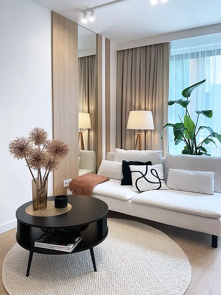 Nowoczesne wnętrze salonu z elementami glamour i japandi, biała sofa, czarny stolik.