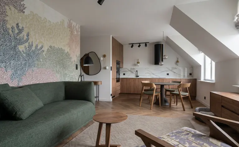Wnętrze salonu z zieloną sofą, drewnianymi meblami i akcentami art deco oraz skandynawskim stylem.