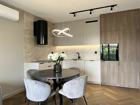 Wnętrze nowoczesnej kuchni z szarymi meblami i okrągłym stołem.