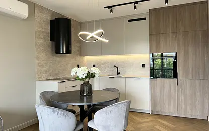 Wnętrze nowoczesnej kuchni z szarymi meblami i okrągłym stołem.