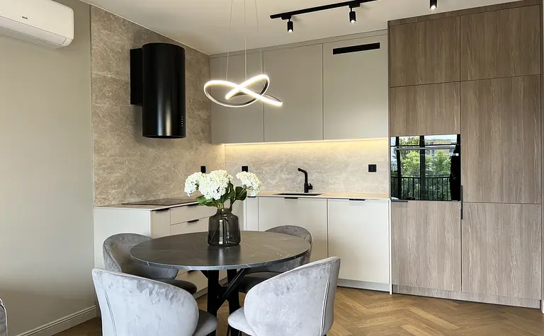 Wnętrze nowoczesnej kuchni z szarymi meblami i okrągłym stołem.