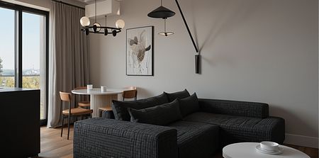 Wnętrze salonu z minimalistycznym wystrojem, industrialnymi akcentami, szarymi ścianami oraz czarną sofą.