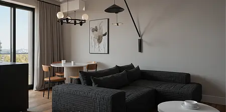 Wnętrze salonu z minimalistycznym wystrojem, industrialnymi akcentami, szarymi ścianami oraz czarną sofą.