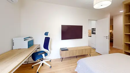 Wnętrze pokoju w stylu skandynawskim z biurkiem, telewizorem i szafką.