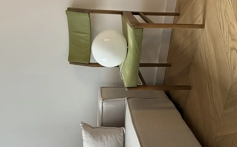 Pokój w stylu boho z minimalistycznym fotelem i rustykalnym oświetleniem.