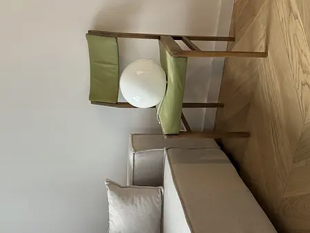 Pokój w stylu boho z minimalistycznym fotelem i rustykalnym oświetleniem.