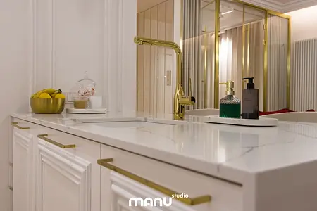 Nowoczesna łazienka z białą umywalką i złotymi elementami, tradycyjny design.