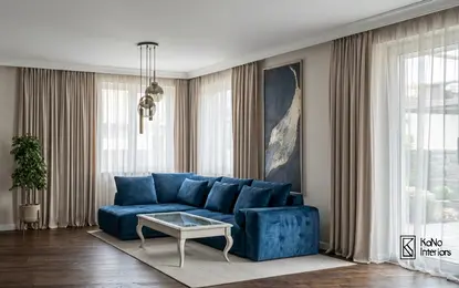 Wnętrze salonu z niebieską sofą, białym stolikiem i rośliną w tradycyjnym stylu.