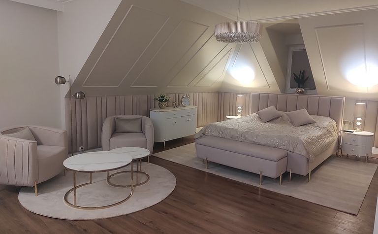 Sypialnia w stylu glamour z jasnym łóżkiem, lampami i eleganckim wystrojem.