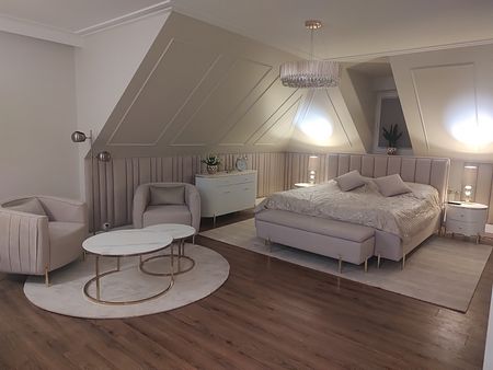 Sypialnia w stylu glamour z jasnym łóżkiem, lampami i eleganckim wystrojem.