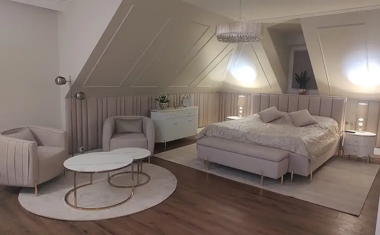 Sypialnia w stylu glamour z jasnym łóżkiem, lampami i eleganckim wystrojem.
