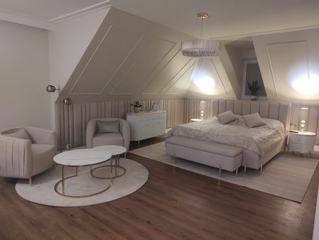 Sypialnia w stylu glamour z jasnym łóżkiem, lampami i eleganckim wystrojem.