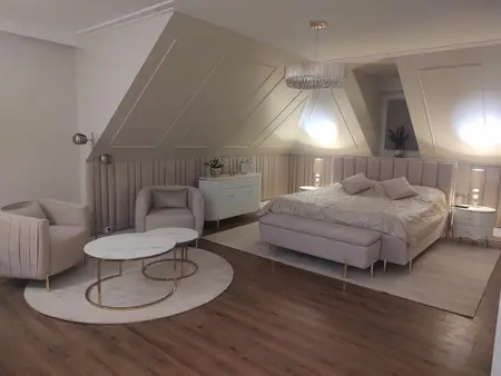 Sypialnia w stylu glamour z jasnym łóżkiem, lampami i eleganckim wystrojem.