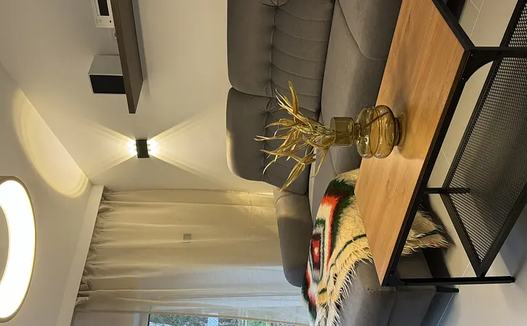 Wnętrze salonu w stylu boho, minimalistycznym i rustykalnym z szarym narożnikiem.