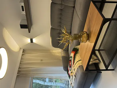 Wnętrze salonu w stylu boho, minimalistycznym i rustykalnym z szarym narożnikiem.