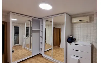 Garderoba w stylu minimalistycznym z lustrami i białymi meblami.