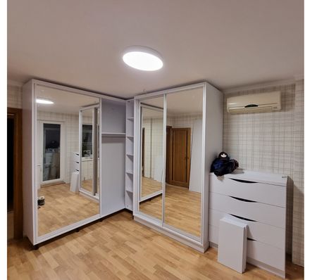 Garderoba w stylu minimalistycznym z lustrami i białymi meblami.
