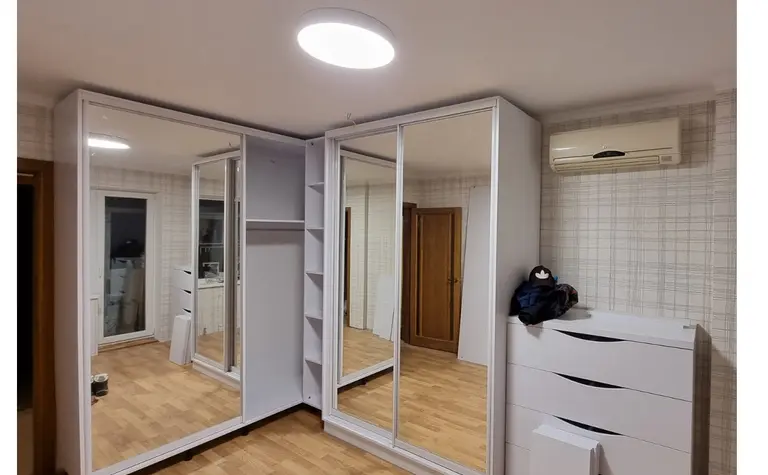 Garderoba w stylu minimalistycznym z lustrami i białymi meblami.