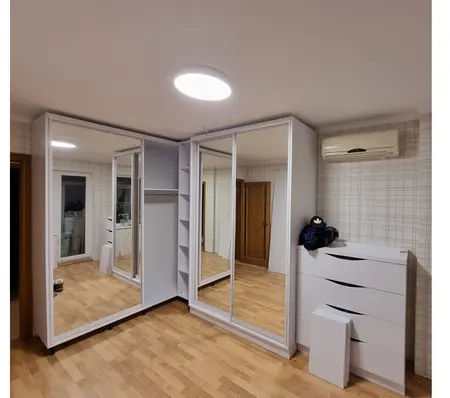 Garderoba w stylu minimalistycznym z lustrami i białymi meblami.