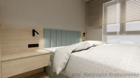 Sypialnia z niebieskim zagłówkiem, jasną pościelą i drewnianym meblem w stylu industrialnym, minimalistycznym.