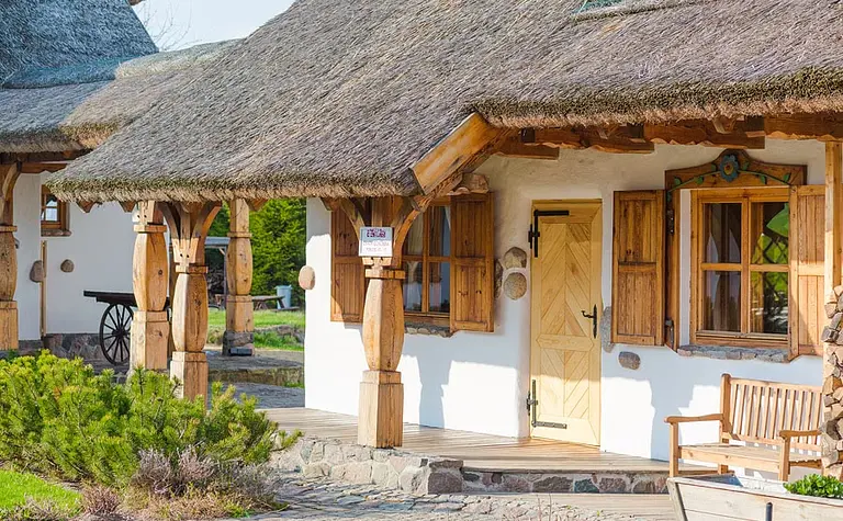 Zewnętrzny widok rustykalnego domu z drewnianymi elementami i strzechą, styl boho, eklektyczny, minimalistyczny.