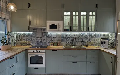 Kuchnia w stylu boho, eklektycznym i rustykalnym z zielonymi meblami i dekoracyjnymi kafelkami.