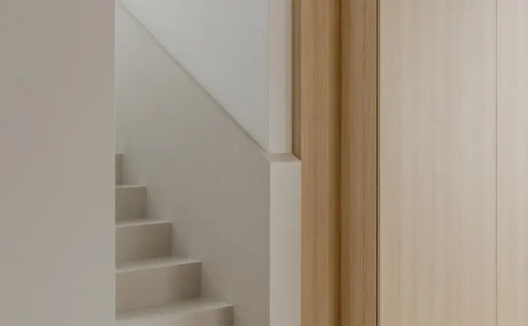 Wnętrze w stylu japandi z minimalistycznymi schodami i drewnianymi szafkami.