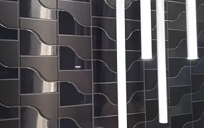 Nowoczesne wnętrze z ciemnymi kaflami w faliste wzory i białymi lampami.