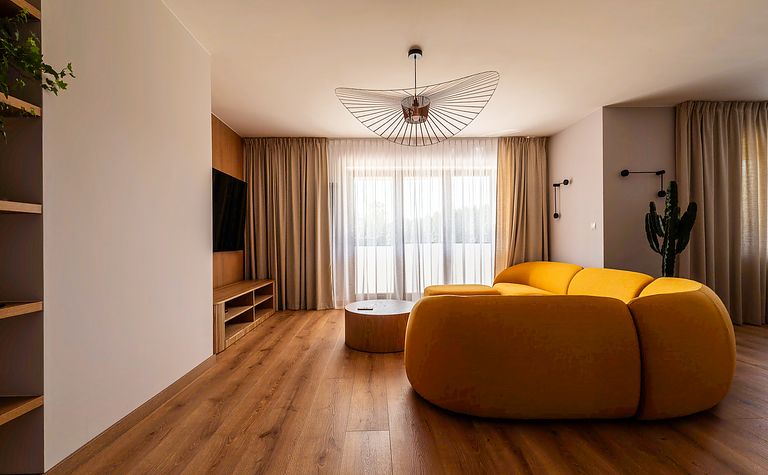 Wnętrze salonu z żółtą sofą, drewnianymi elementami, minimalistyczny design, skandynawski styl.