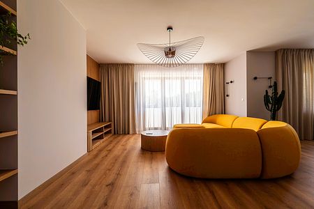 Wnętrze salonu z żółtą sofą, drewnianymi elementami, minimalistyczny design, skandynawski styl.