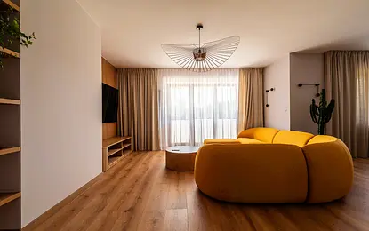 Wnętrze salonu z żółtą sofą, drewnianymi elementami, minimalistyczny design, skandynawski styl.