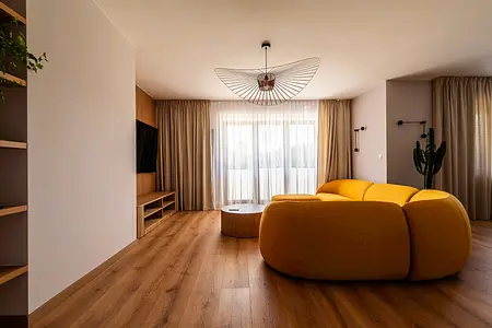 Wnętrze salonu z żółtą sofą, drewnianymi elementami, minimalistyczny design, skandynawski styl.