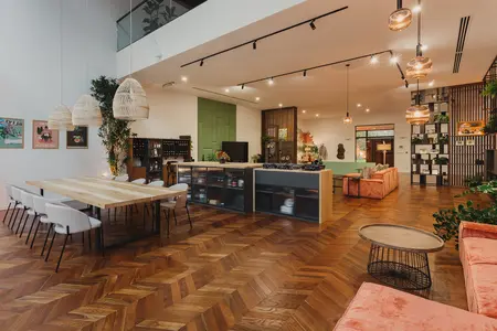Wnętrze z drewnianym stołem, różowymi sofami i roślinami w stylu dopamine decor, eklektycznym, industrialnym, rustykalnym, vintage.