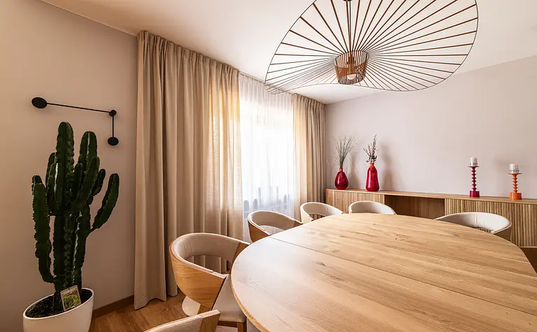 Wnętrze jadalni z okrągłym stołem, drewnianymi krzesłami i roślinami. Styl boho, industrialny i skandynawski.